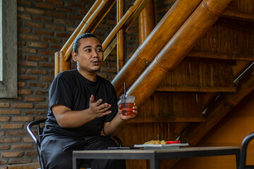 Young Asian man, digital nomad working remotely from cafe, using laptop and smartphone. young Asian men are hanging out in a cafe with an industrial theme