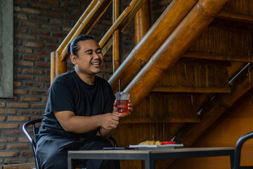 Young Asian man, digital nomad working remotely from cafe, using laptop and smartphone. young Asian men are hanging out in a cafe with an industrial theme