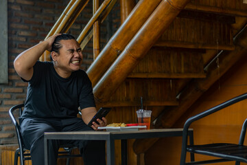 Young asian men, digital nomad working remotely from a cafe, using smartphone.