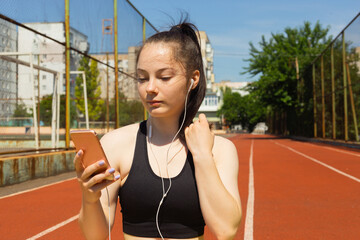 Sport and technology. A beautiful young woman with a ponytail sitting resting after workout during...