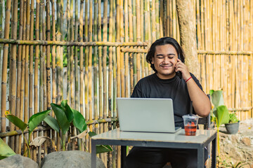 Young asian men, digital nomad working remotely from a cafe, drinking coffee and using laptop.