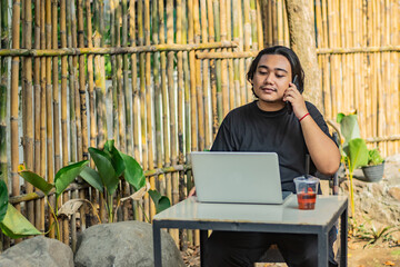 Young asian men, digital nomad working remotely from a cafe, drinking coffee and using laptop.