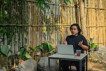 Young asian men, digital nomad working remotely from a cafe, drinking coffee and using laptop.