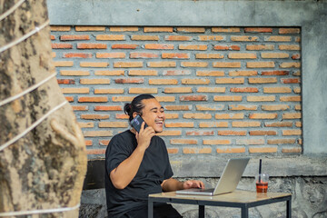 Young asian men, digital nomad working remotely from a cafe, drinking coffee and using laptop.