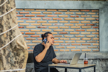 Young asian men, digital nomad working remotely from a cafe, drinking coffee and using laptop.
