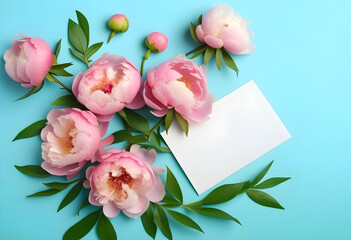 Fototapeta premium A flat lay of pink peonies and a blank card on a light blue background