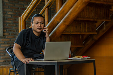 Young asian men, digital nomad working remotely from a cafe, using  smartphone.