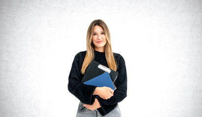 Young woman with long hair holding folders against a white backg