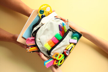 Donation box with school supplies in hands on color background. Donation, charity concept.