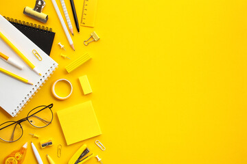 Vibrant Office Supplies on Yellow Background. Flat lay notebooks, pencils, glasses, and sticky...