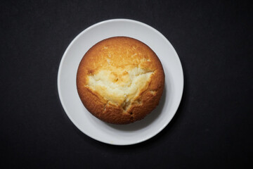 Cupcake in a white saucer on a black background
