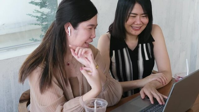 Smiling couple Asian woman is friendship workmate and online shopping in social media platform with smartphone. Technology with businesswomen are working together
