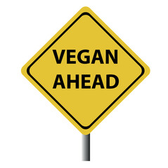 A yellow and black diamond shaped road sing with the words vegan ahead making a great concept.