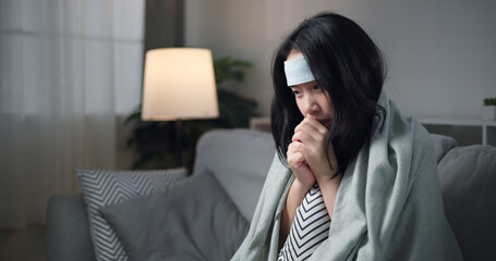 Portrait of Unwell young woman having a cold, sneezing and blowing your nose while sitting on sofa in the living room at home, healthcare woes