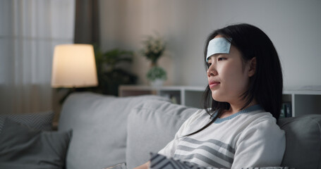 Portrait of Unwell young woman have a fever sitting absentmindedly on the sofa in the living room...