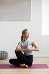 Fototapeta premium Woman meditating, practicing yoga, doing relaxation exercises at home. Meditation, yoga, balance, mindfulness, workout, relaxation, healthy lifestyle concept