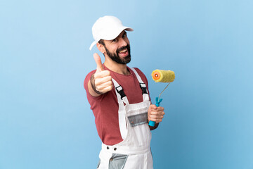 Adult painter man over isolated blue background with thumbs up because something good has happened