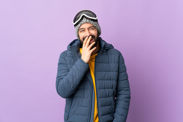 Skier man with snowboarding glasses over isolated purple background happy and smiling covering mouth with hand