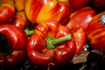 A close up of red striped bell peppers on a stall in the sunshine