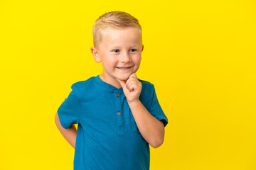 Little Russian boy isolated on yellow background looking to the side and smiling