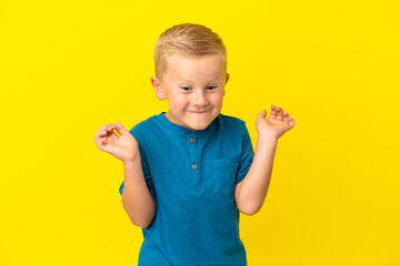 Little Russian boy isolated on yellow background having doubts while raising hands