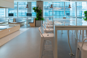Interior of modern empty office lobby.Open ceiling design.There are floor-to-ceiling Windows and comfortable white chairs and table.