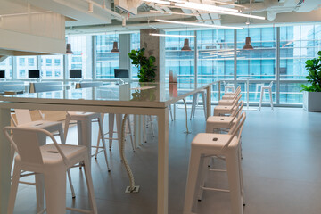 Interior of modern empty office lobby.Open ceiling design.There are floor-to-ceiling Windows and comfortable white chairs and table.