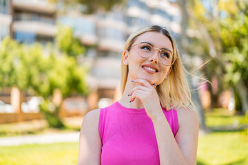 Fototapeta premium Young pretty blonde woman at outdoors With glasses and thinking while looking up