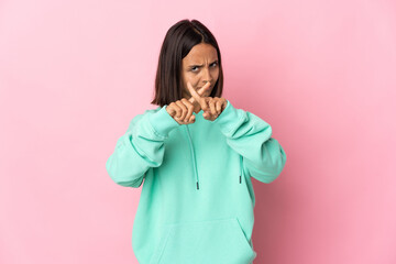 Young latin woman isolated on pink background making stop gesture with her hand to stop an act