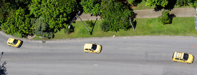 Three yellow Colombian taxis in a row. Aerial minimalist picture taken from above. Medellin (Medellín), Antioquia, Colombia.