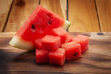 Close-up of watermelon Slice and Cubes (Citrullus Lanatus), on a wooden background.