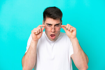 Young caucasian man isolated on blue background With glasses and frustrated expression