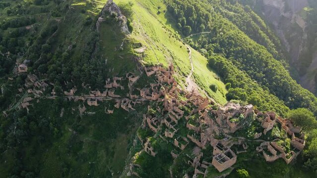 Old stone houses in abandoned Gamsutl mountain village in Dagestan, Russia. Beautiful view of the mountains at sunset. Aerial drone view. Summer landscape
