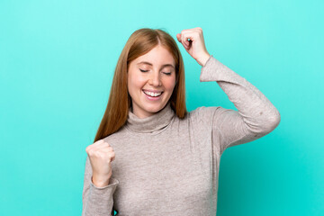 Young redhead woman isolated on blue background celebrating a victory