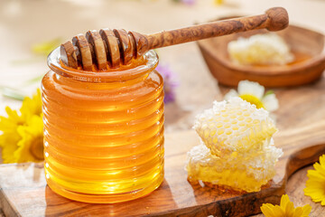 Natural organic honey in glass jar, honey dipper and honeycombs are near. Natural food background.