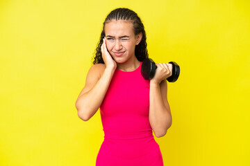 Young sport woman making weightlifting isolated on yellow background frustrated and covering ears