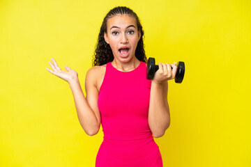 Young sport woman making weightlifting isolated on yellow background with shocked facial expression