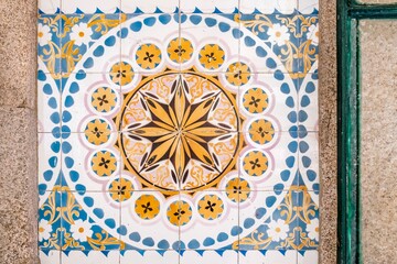 Old Portuguese typical tiles, called azulejos taken from the external walls of an old house. Ceramic tile with a yellow sun shape and surrounded by blue borders.