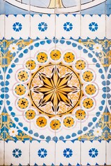 Old Portuguese typical tiles, called azulejos taken from the external walls of an old house. Ceramic tile with a yellow sun shape and surrounded by blue borders.