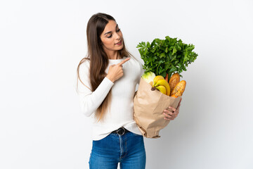 Young caucasian woman buying some food isolated on white background pointing to the side to present a product