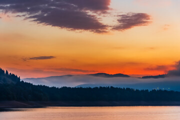 Fototapeta premium Ceahlau mountain silhouette against a sunset sky over water