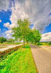 Big clouds almost touching the country road in a rural landscape in The Netherlands.