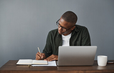 Office, laptop and black man writing notes for research, schedule and online information in...