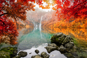 Amazing in nature, beautiful waterfall at colorful autumn forest in fall season with lake	
