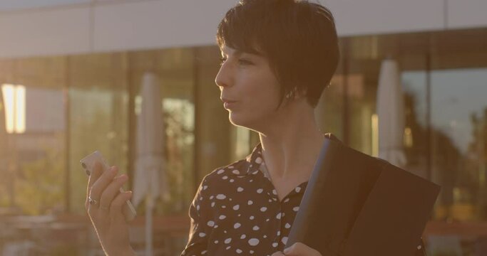Woman using smartphone against urban backdrop. Technology and modern lifestyle. Sense of connectivity, efficiency, and adaptability humans in the digital era. Video AI chat bot assistent using.
