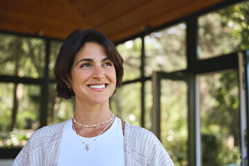 Young happy confident Hispanic woman health coach, yoga instructor, holistic teacher looking away standing in yoga studio advertising retreat mind body health therapy classes. Copy space.