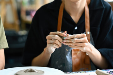 Close-up of an artist's hands molding clay with precision, showcasing the detailed process of...