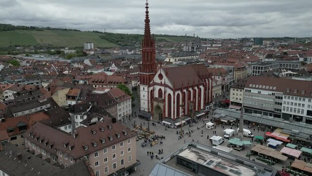Drone footage Maria Chappel with street marketplace and European style buildings around in Wurzburg