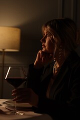 Beautiful young woman with glass of wine at table in restaurant