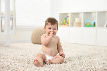 Cute baby boy sitting on carpet at home